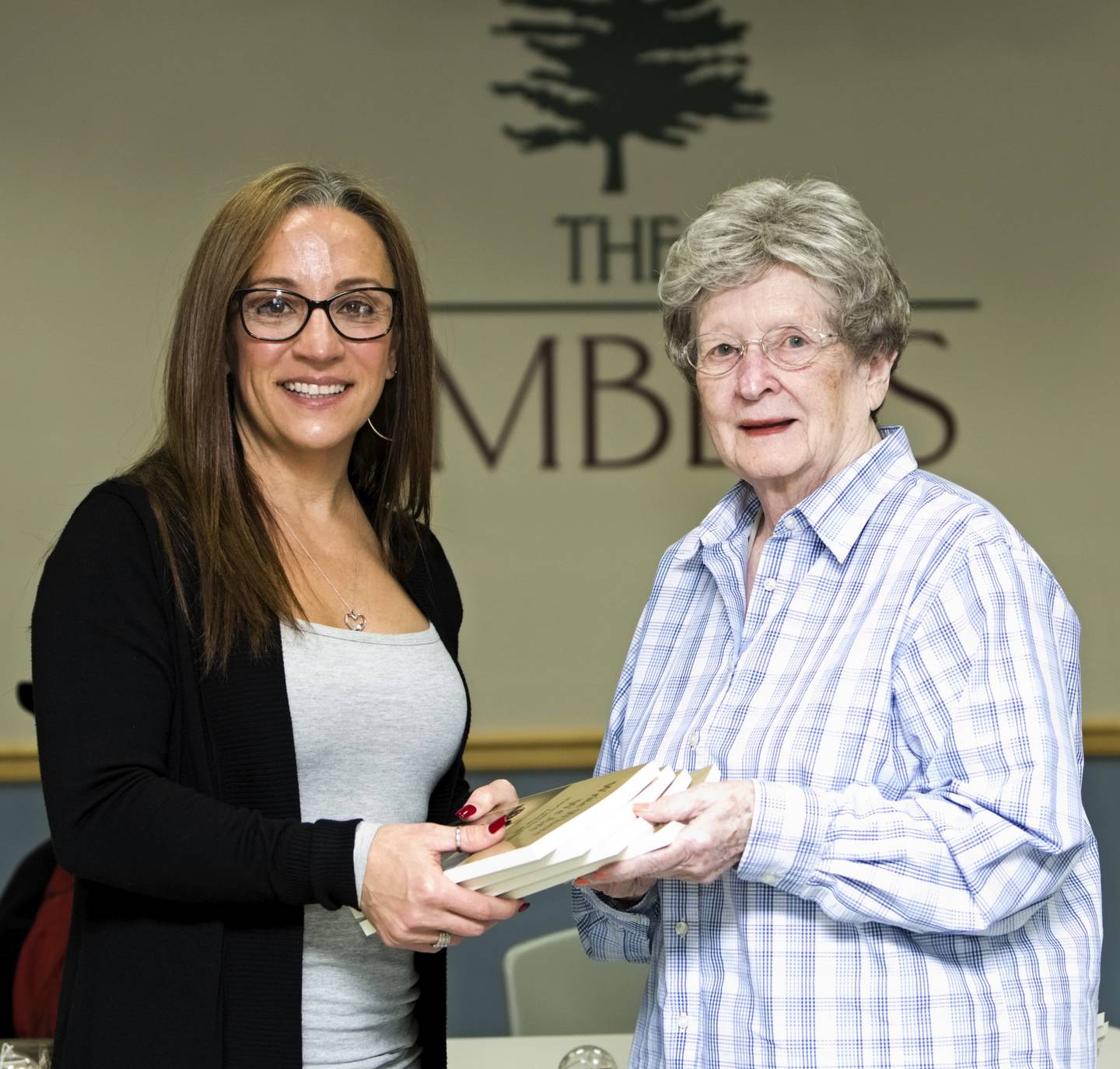 Angie Aegerter of Channahon, left, donated funds that were used to buy copies of WriteOn Joliet’s fifth anthology. Jeanette Langebartels, right, president of the Timbers of Shorewood’s resident council, accepts the anthology on behalf of the book club. Thursday, November 9, 2023 Shorewood Ill.