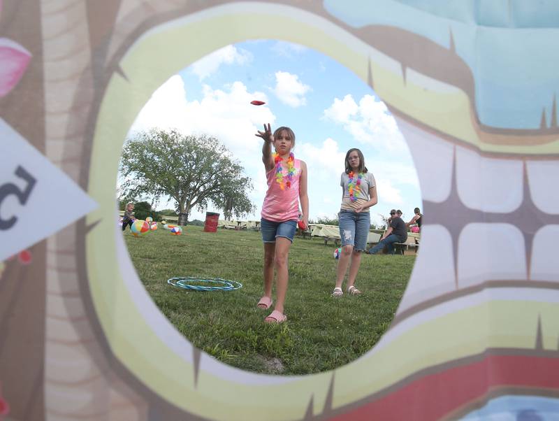 Ava Gordan and her friend Veronica Donnelly toss bean bags into a hole while playing a game during Marseilles Fun Days on Tuesday, June 24, 2025 at the Marseilles Community Boat Launch. The festival featured Jimmy Buffett themed music, kids games and a ducky derby. Marseilles Fun Days runs through Sunday with different themed-nights.