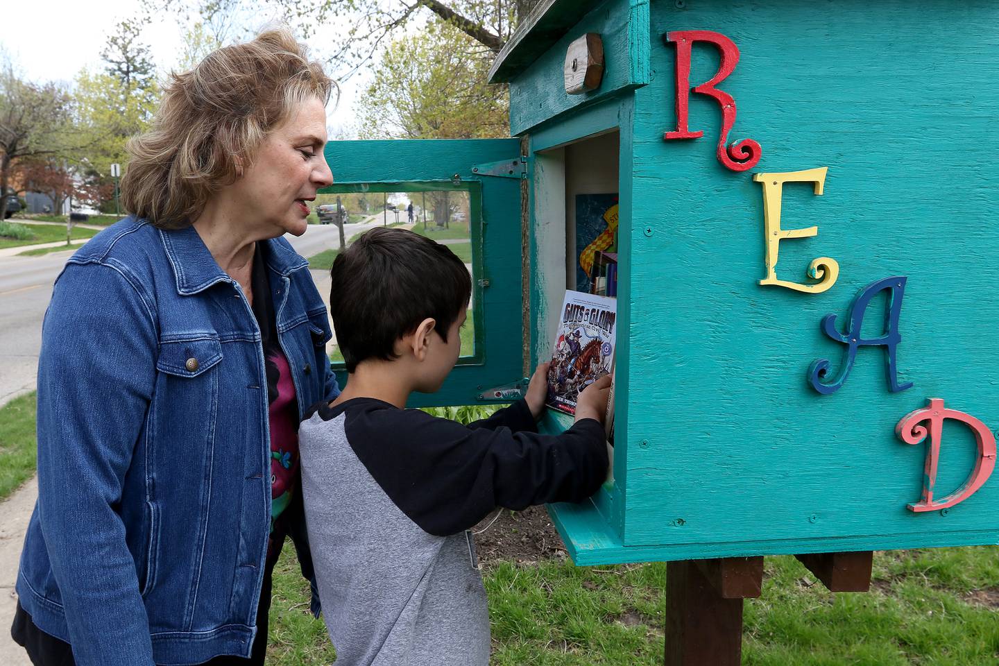 Chris Chirchirillo and Jaxen Esparza, 8, pick out a new book to read from the little free library at the end of her block on Saturday, April 24, 2021 in Lake in the Hills. Chirchirillo is one of 24 people to receive an outpatient robotic lung surgery at Northwestern Medicine and, four months later, is enjoying returning to normal activities.