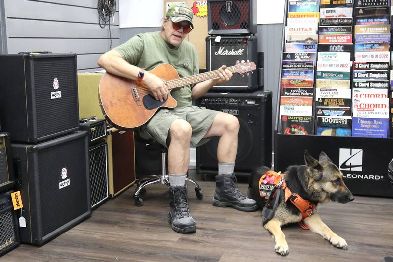 U.S. Marine Corps veteran Marshall Boyle, from DeKalb, plays guitar with his German Shepherd service dog, Lucy, Friday, Sept. 22, 2023, at Aurora Music Company in DeKalb. Boyle serves as an ambassador to Guitars 4 Vets and volunteers for Habitat for Humanity.