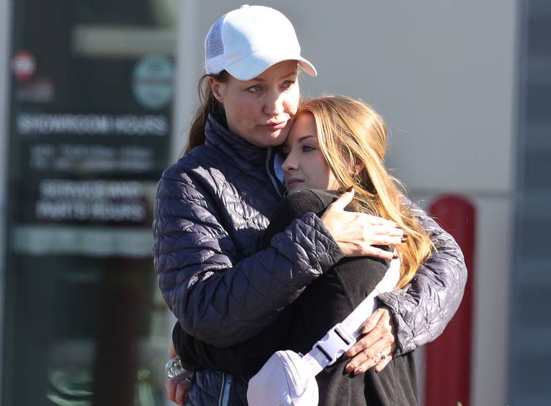 Two women hug among a group of Brian Bemis Toyota employees Wednesday, Oct. 23, 2024, outside the dealership in DeKalb after police responded to a stabbing where multiple employees were injured. The incident ended after police shot the man wielding the knife authorities said.