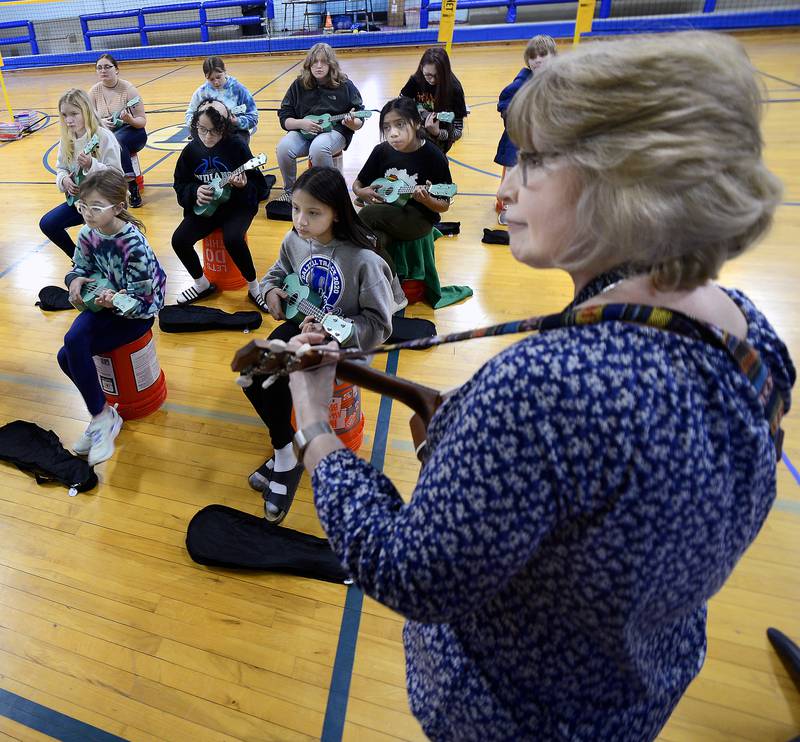 Dalzell Grade School music teacher Chris Kelsey leads 13 ukulele students in a song during a recent class Wednesday, March 15, 2023.