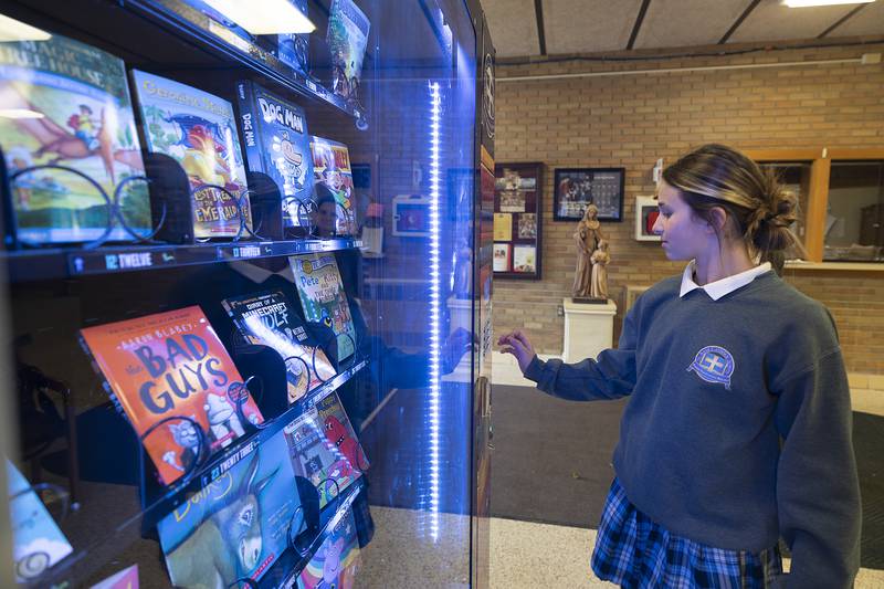 Raelie Bilharz, sixth grader at St. Anne’s, drops in a token to test the book vending machine Wednesday, Jan. 22, 2025. Students earn tokens to purchase the books by meeting academic goals.