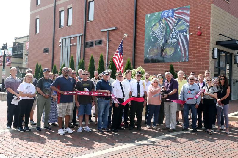 The ribbon is cut Thursday, Aug. 22, 2024, during the DeKalb Veterans Memorial Mural dedication. The mural, which is  is a re-creation of a painting by Mary Gallagher Stout titled “What These  Boots Have Seen,” is on the rear wall of the Plaza DeKalb building overlooking Van Buer Plaza.
