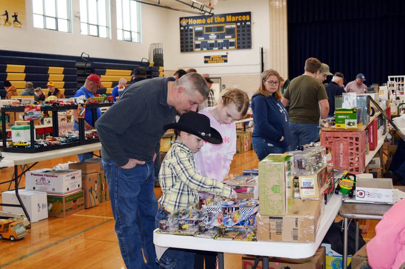 Justin House, of Chadwick, stands behind his children, Kelsie House, 11, and Clayton House, 7, look at Hot Wheels products available for sale at the Polo Lions Club’s 38th Farm Toy Show on March 4. The event was held at Polo Community High School.