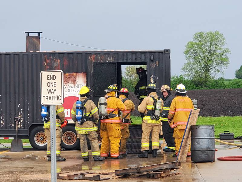 Operators controlled the airflow through the doors located on the side of a simulator during firefighter training on Saturday. Participants were seated on the ground, facing forward, as the flashover conditions were formed in front of them.