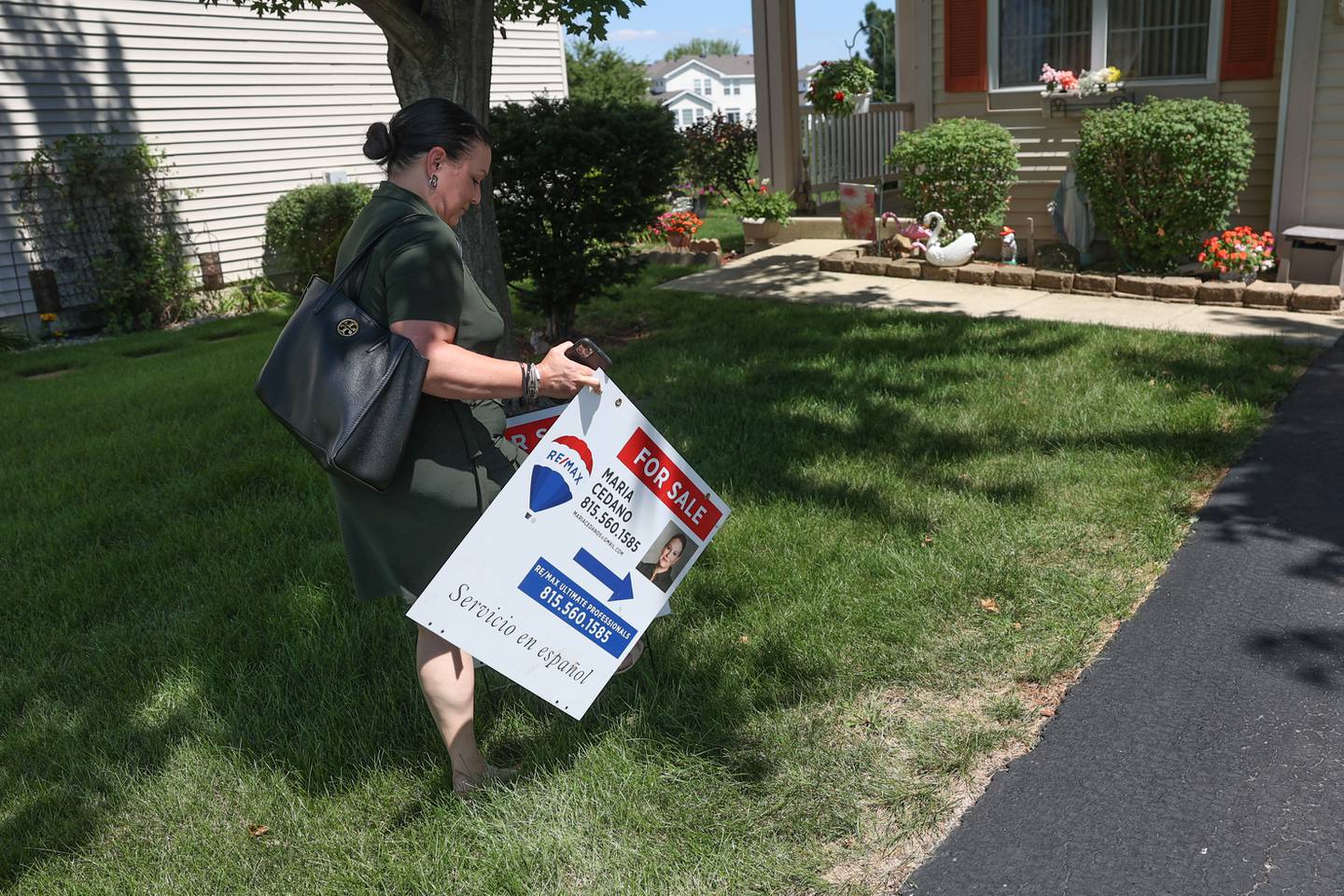 Maria Cedano, a realtor with ReMax, puts up a For Sale sign in the yard of a home in Crest Hill. Wednesday, Aug. 10, 2022, in Crest Hill.