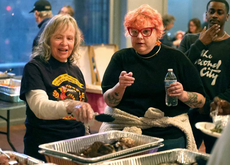Volunteer Inge Nicklas, (left) from DeKalb, and Ash Rootes, executive director of DeKalb Mutual Aid, talks about some of the food available Wednesday, Nov. 26, 2025, during A World of Thanks, Community Thanksgiving hosted by DeKalb Mutual Aid at the McCabe’s building in DeKalb.