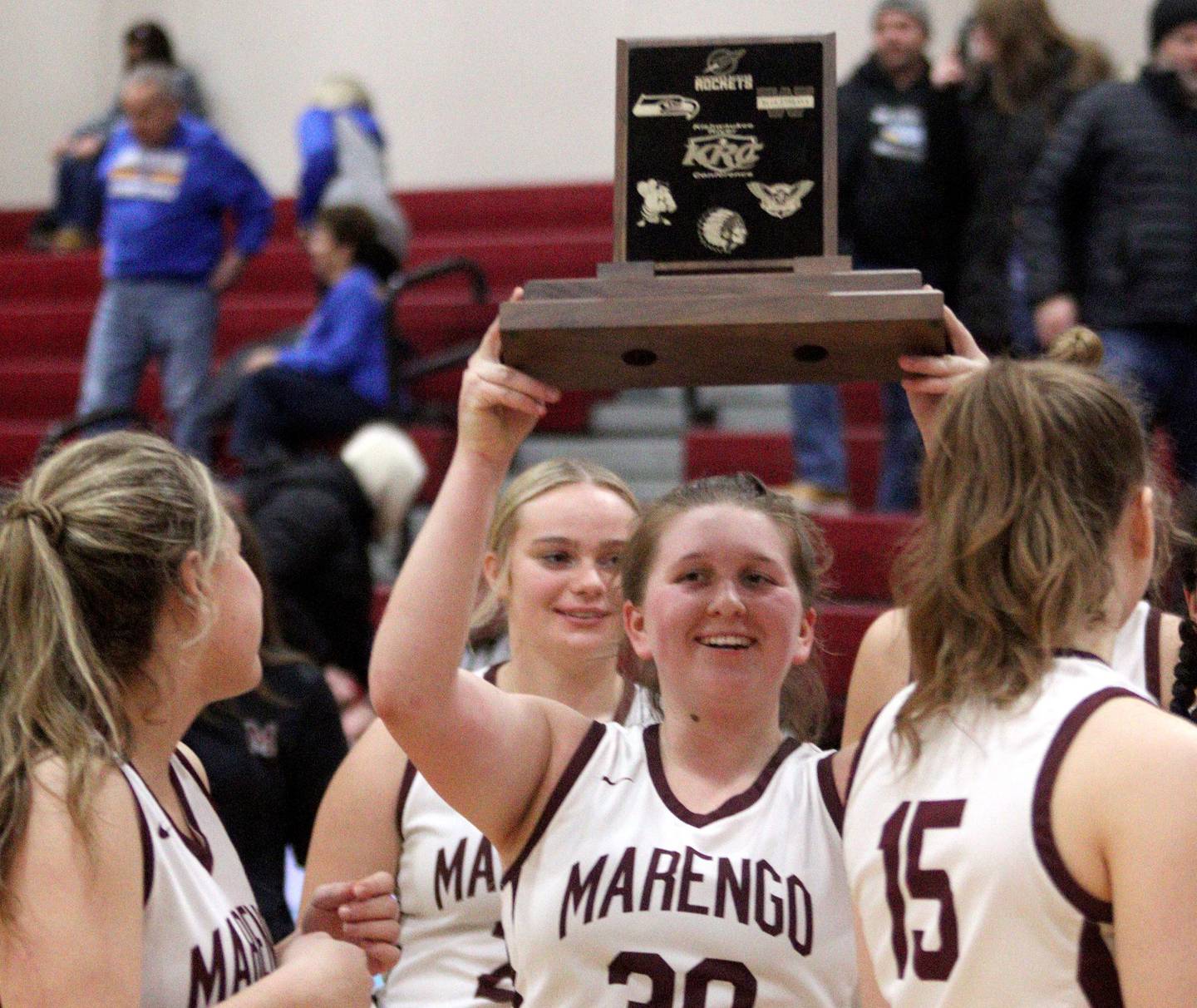 Marengo’s Addie Johnson hoists the hardware as the Indians clinched a conference title with a Tuesday victory over Johnsburg at Marengo.