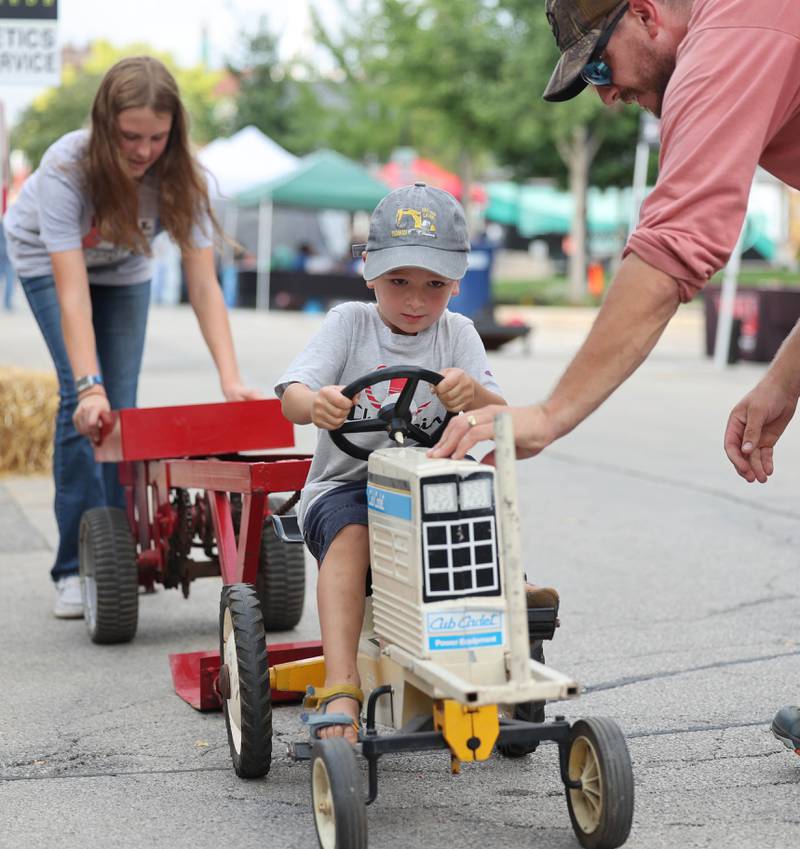 Abram Quinn, 3, from DeKalb, gives it his all at the pedal tractor pull with his dad Shea during Corn Fest Friday, Aug. 25, 2023, in downtown DeKalb.