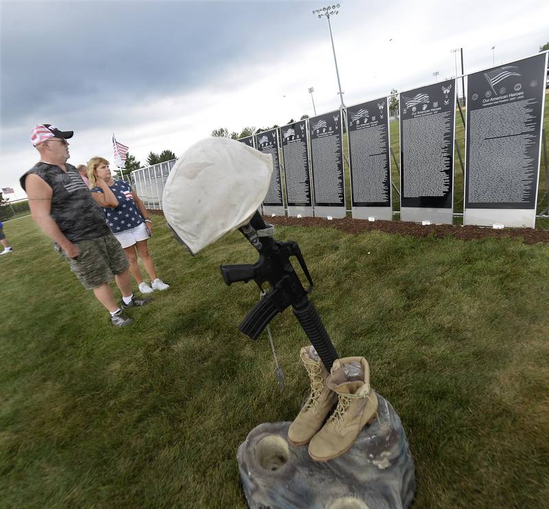 A couple view the replica of the Middle East Conflicts Wall Saturday at Veterans Memorial Park in Peru prior to a ceremony honoring the names of those who are on the wall.