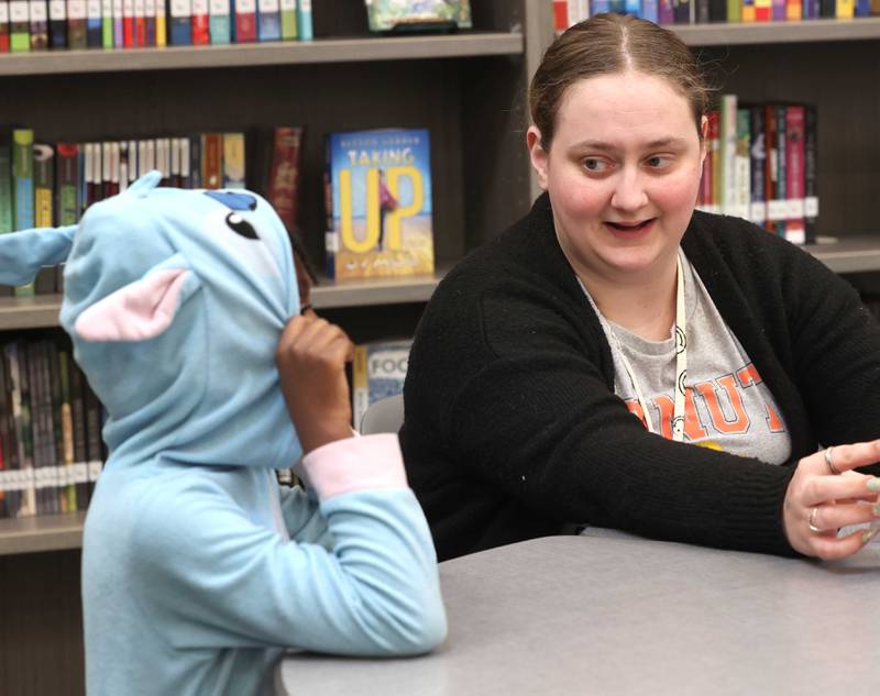 Mitchell Elementary School first grade teacher Cassandra Sprankle talks to student Savannah Holden Thursday, March 19, 2026, in the library at the school in DeKalb.