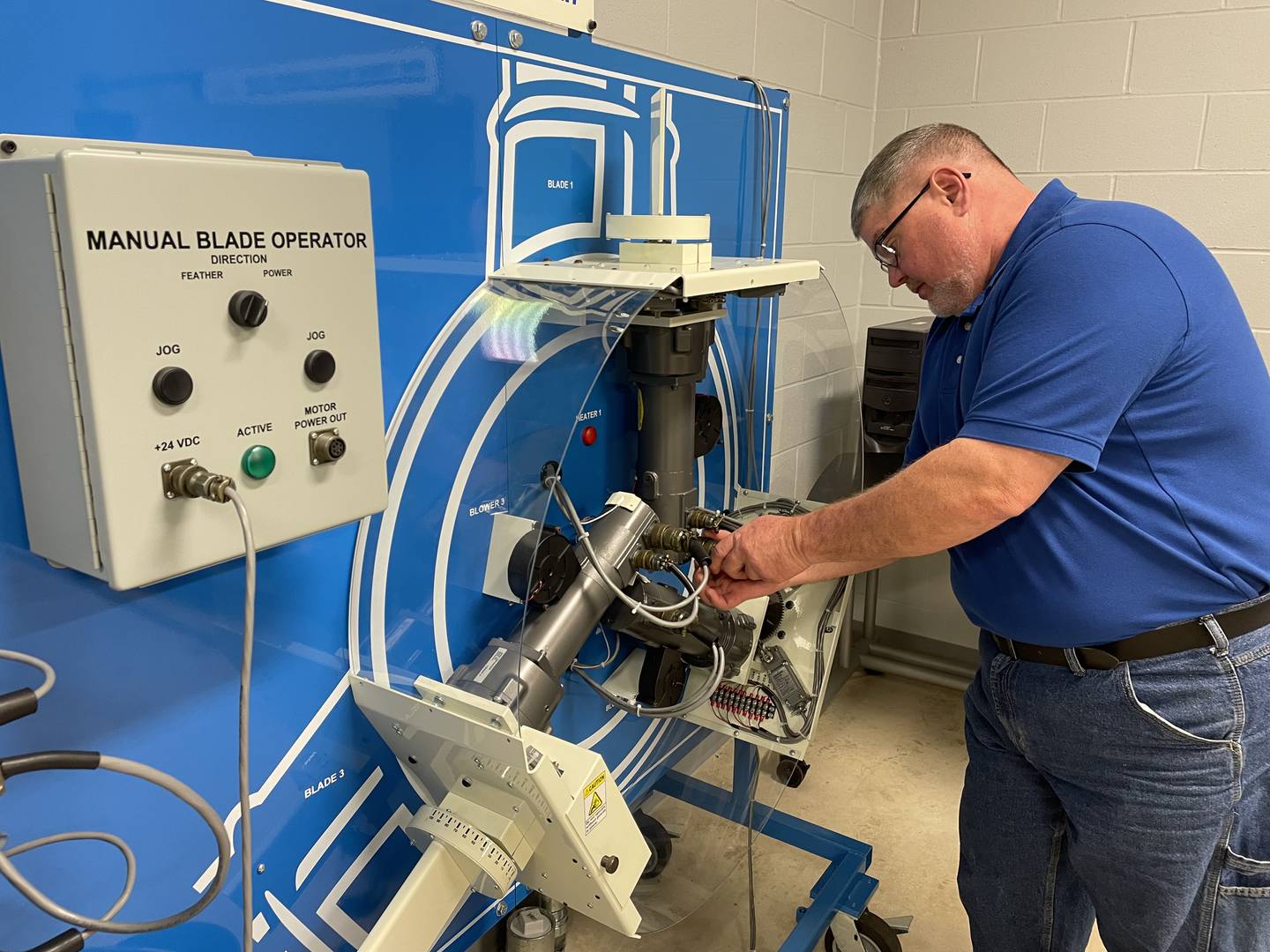 Wind technology instructor Steve Malavolti adjusts a hose on the Hub Learning System/Manual Blade Operator.