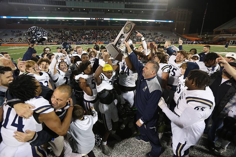 Members of the IC Catholic football team hoist the Class 3A State Championship trophy on Friday, Nov. 25, 2022 at Memorial Stadium in Champaign.