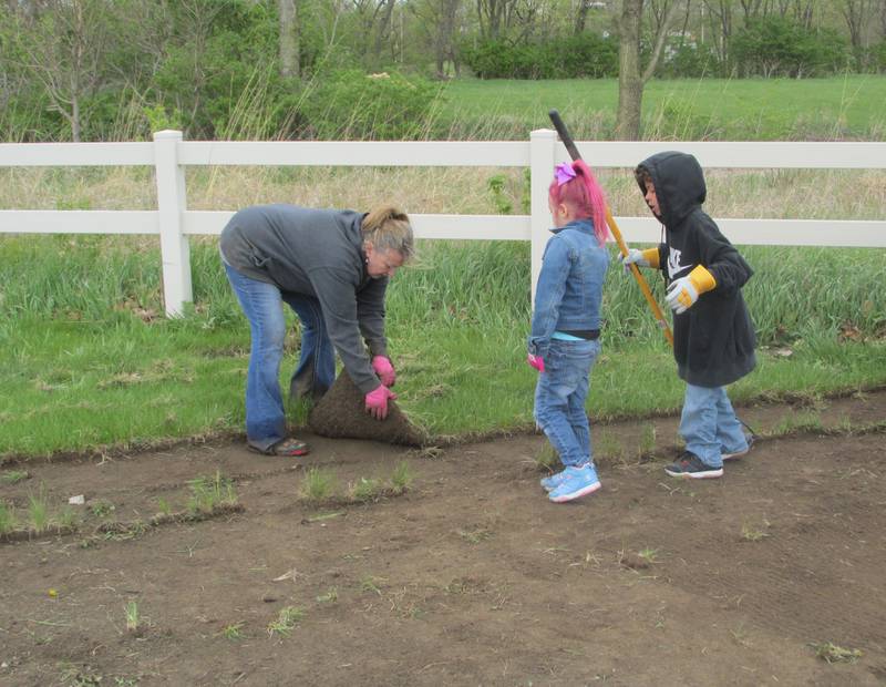 Volunteer Nina Vaughn pulls up sod Saturday, April 22, 2023, at the Hopalong Cassidy Canoe Launch in Streator to get it ready for the planting of a pollinator garden to attract monarch butterflies. She is joined by assistants Karsyn Vaughn-Scott (left) and Kamari Johnson.