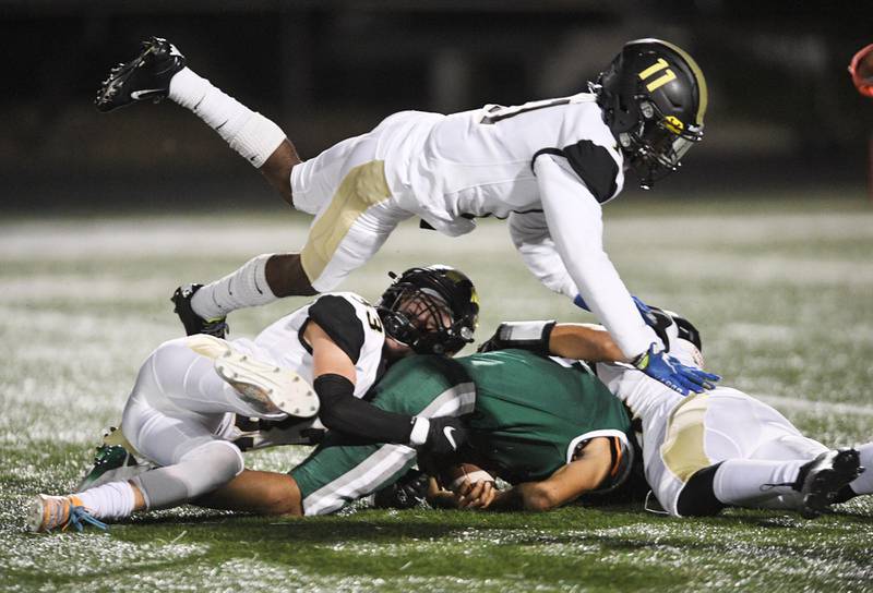 Graylake North's DeAndre Neely Jr. flies over the top of teammates Ethan Case and Gavin Mercier, right, as they bring down Grayslake Central ballcarrier Jeremiah Poyser in a football game at Central on Friday, September 10, 2021.