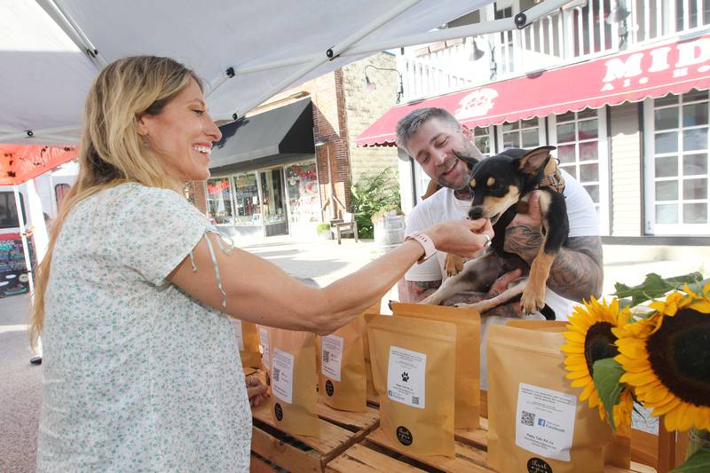 Laura Russo, of Richmond with the Happy Tails Pet Co. gives a treat to a dog named, Farley, held by his owner, Jesse Schramel, of Wauconda at the Wauconda Farmers’ Market in downtown Wauconda. The farmers’ market runs on Thursday afternoons from 4-7pm through September 29th