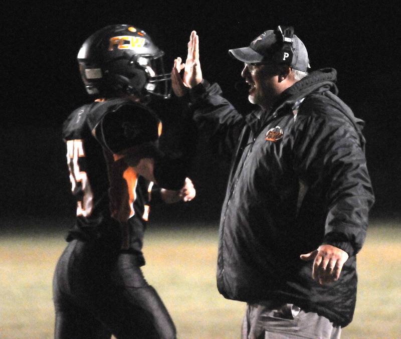 Flanagan-Cornell/Woodland junior Kesler Collins high-fives head coach Todd Reed after a hard-nosed first-down catch and run Friday, Oct. 7, 2022, at the Wood Shed in rural Streator.