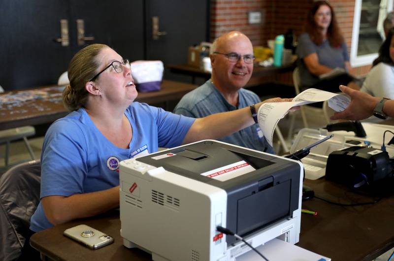 Election judges Denise Ross and Paul Horvatin assist a voter in the General Primary Election at Downers Grove North High School on Tuesday, June 28, 2022.