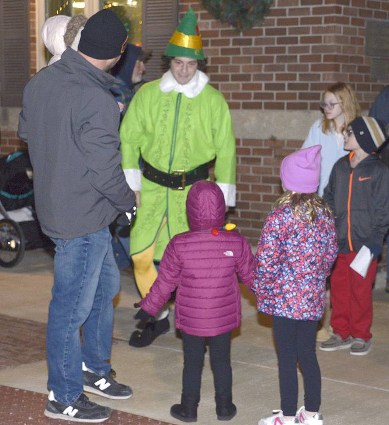 Buddy the Elf visits with those along Mill St in Utica waiting for for Santa to arrive Saturday during the annual Utica Fire Dept. Santa Parade.