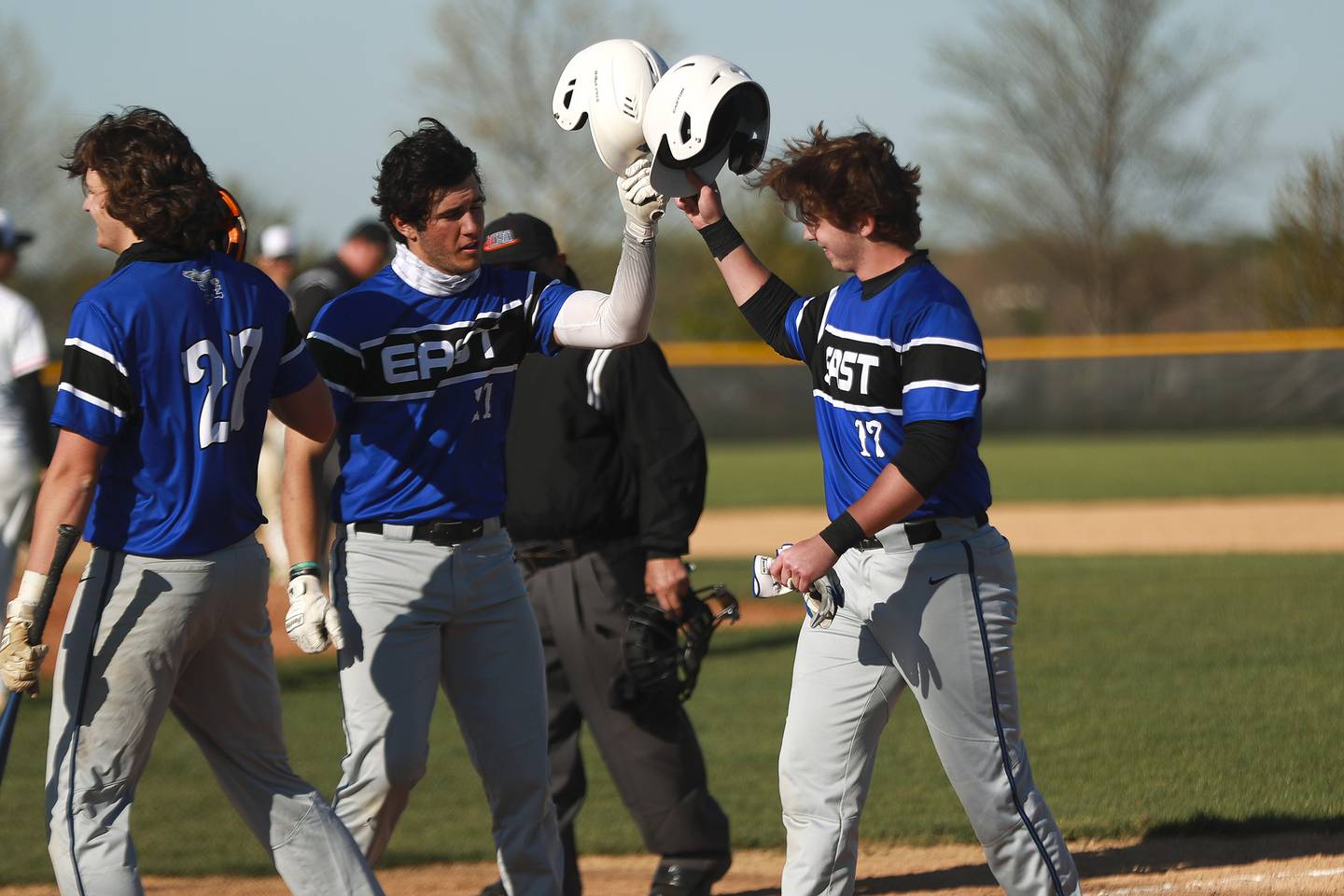 Lincoln-Way East's Randy Seymour (center) and Jake Petak (right) bump helmets after scoring on Friday, April 30, 2021, at Lincoln-Way West High School in New Lenox, Ill.
