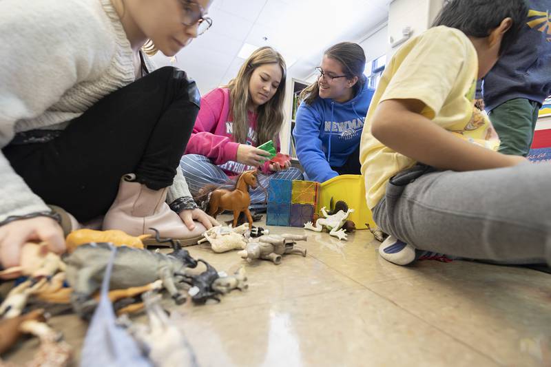 Newman Central Catholic High School juniors Makaila Craft (left) and Leah Kalina figure out some fun things to play with while visiting kindergartners at St. Mary’s School in Sterling on Thursday, Feb. 2, 2023.