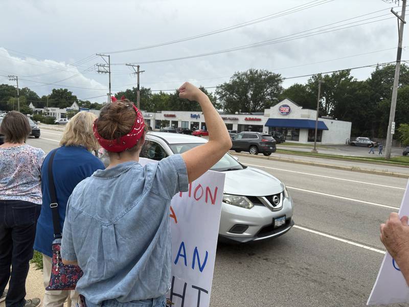 Laura Graveor flexes a muscle during a protest against President Trump in McHenry July 26, 2025.