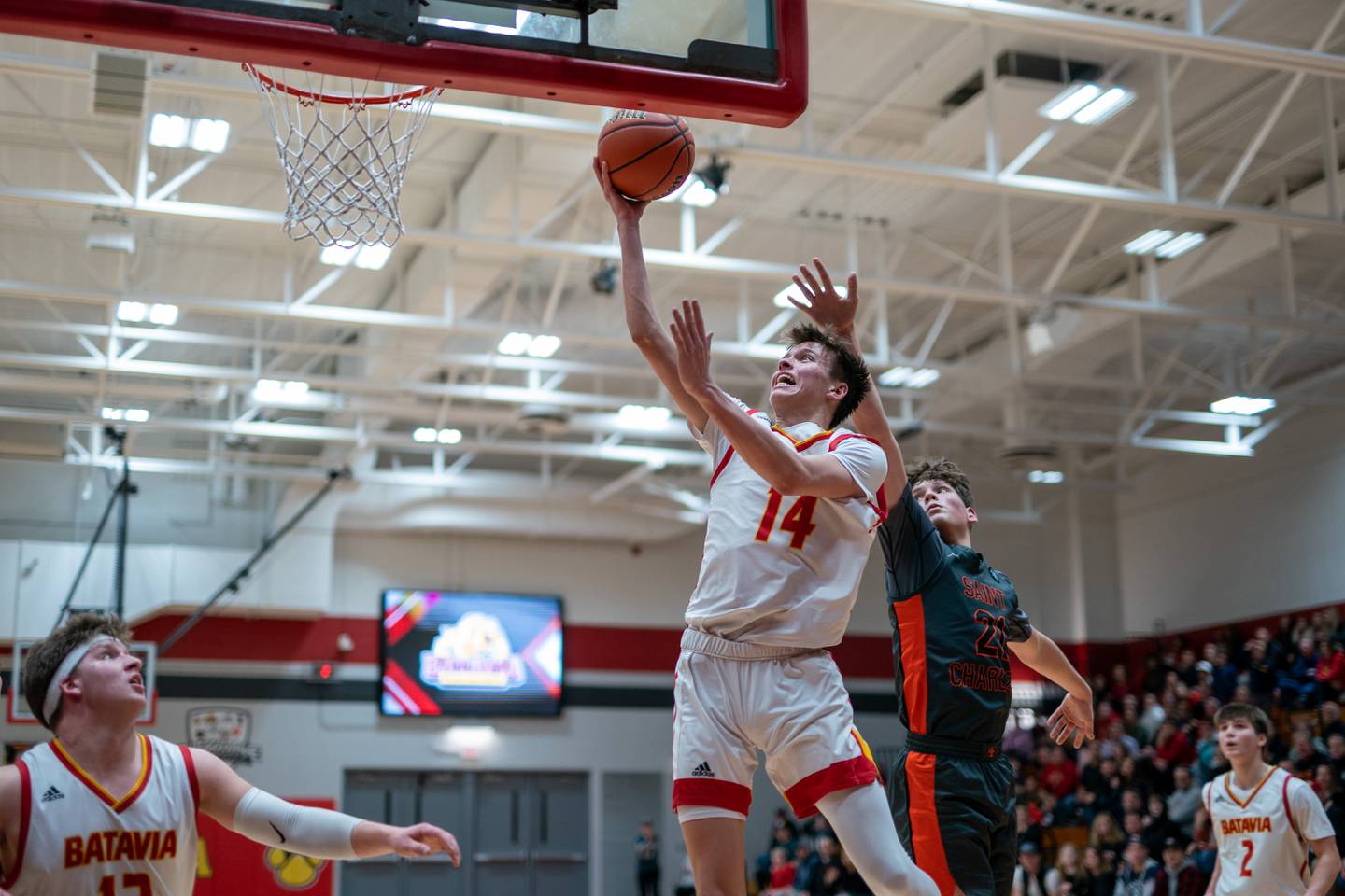 Batavia’s Jack Ambrose (14) drives to the basket against St. Charles East's Jacob Vrankovich (21) during a basketball game at Batavia High School on Friday, Feb 10, 2023.