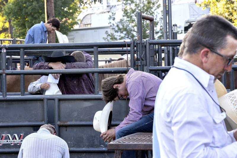 Cowboys bow their heads in prayer Wednesday, August 13, 2025, at the Whiteside County Fair during the Next Level Pro Bronc rodeo.
