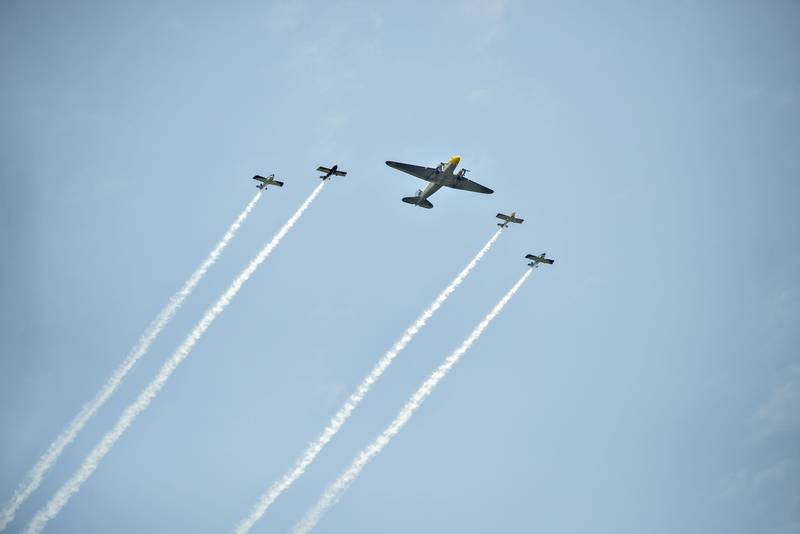 Flanked by smoke-streaming escorts, a Douglas DC-3 makes its rounds at the ACCA Air Show on Saturday, July 24, 2021, at Whiteside County Airport. The plane was built for airline service before being used in World War II as a cargo plane.