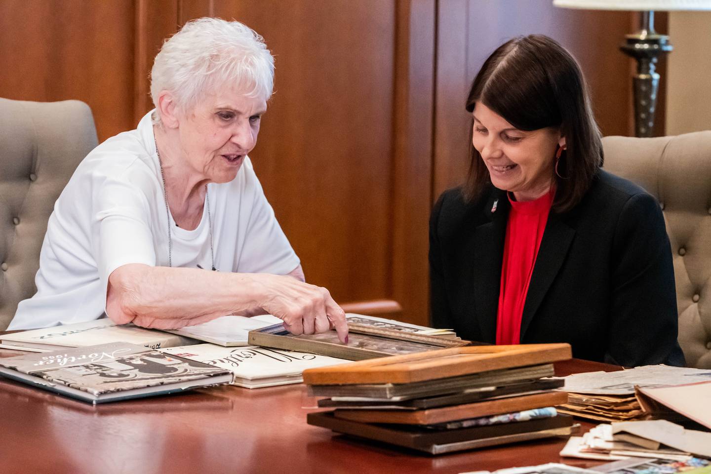 Joyce DeFauw shares photos from her time on campus during the 1950s with Northern Illinois University President Lisa Freeman during a visit to campus in August 2022. Photo provided by NIU.