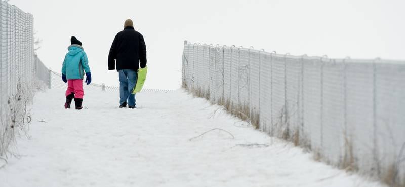 Rick Schwantes and his daughter Samantha, 9 of DeKalb climb the sledding hill at Hopkins Park in DeKalb on Wednesday, Dec. 30, 2020.