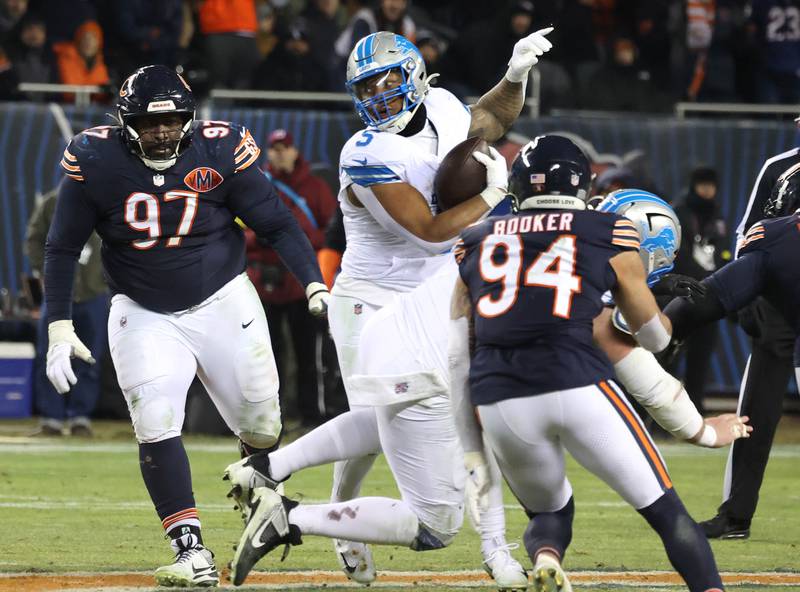 Chicago Bears defensive tackle Andrew Billings (left) and defensive end Austin Booker surround Detroit Lions running back David Montgomery during their game Sunday, Jan. 4, 2026, at Soldier Field in Chicago.