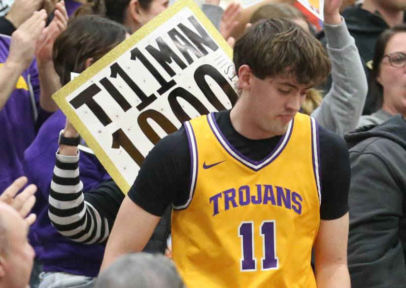 A fan holds a sign that reads "Tillman 1000" as Aden Tillman walks down from the stands after scoring his 1,000th career point on Tuesday, Feb. 3, 2026 at Mendota HIgh School.