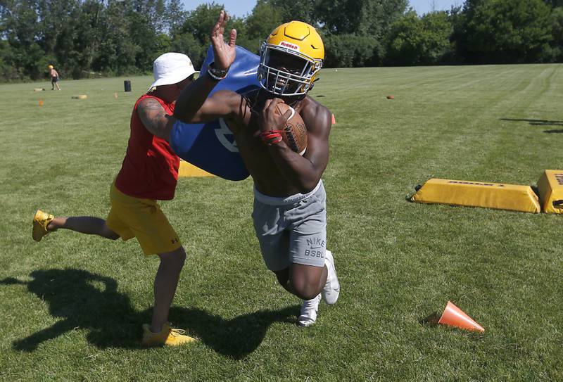 Running back Antonio Brown is hit with a pad by coach Brian Zimmerman as the do a running drill during football practice Monday, June 20, 2022, at Jacobs High School in Algonquin.