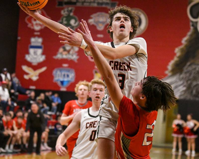 Indian Creek's Logan Schrader, left, makes a basket while being fouled by Aurora Christian's Jacob Baumann (22) during the game on Wednesday Feb. 26, 2025, during the game held at Indian Creek High School.