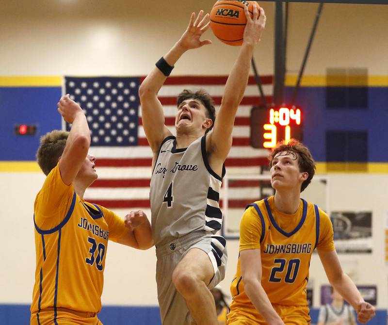 Cary-Grove's Dylan Dumele drives to the basket between Johnsburg's Jayce Schmitt (left) and Josh Kaunas (right) during a Johnsburg Thanksgiving Tournament boys basketball game on Monday, Nov. 24, 2025, at Johnsburg High School.
