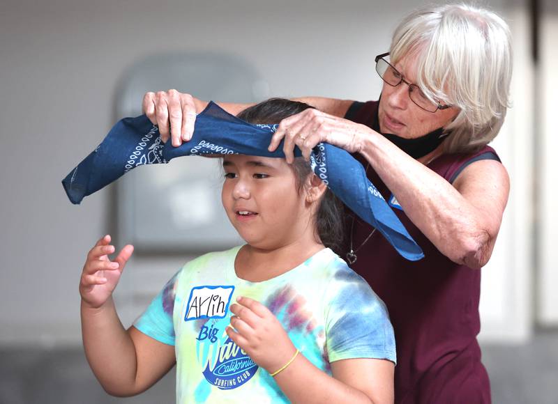 Volunteer Deb Riniker, from Sycamore, helps Aylin Salazar, 7, from DeKalb, get her blindfold on Monday, July 11, 2022, as they get ready for an activity about the sounds of animals on farms during a session of Summer Reading Vacation put on by Neighbors' House in DeKalb in conjunction with the DeKalb County Farm Bureau. Christ Community Church is hosting the camp this week in their outreach center on North 6th Street in DeKalb.