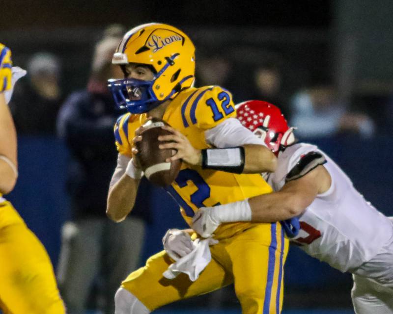 Lyon's Dom Pisciotte (12) is sacked by Naperville Central's Nathan Czachor (25) during Class 8A quarterfinal football game between Naperville Central at Lyons on Friday, Nov 15, 2024  in Western Springs.
