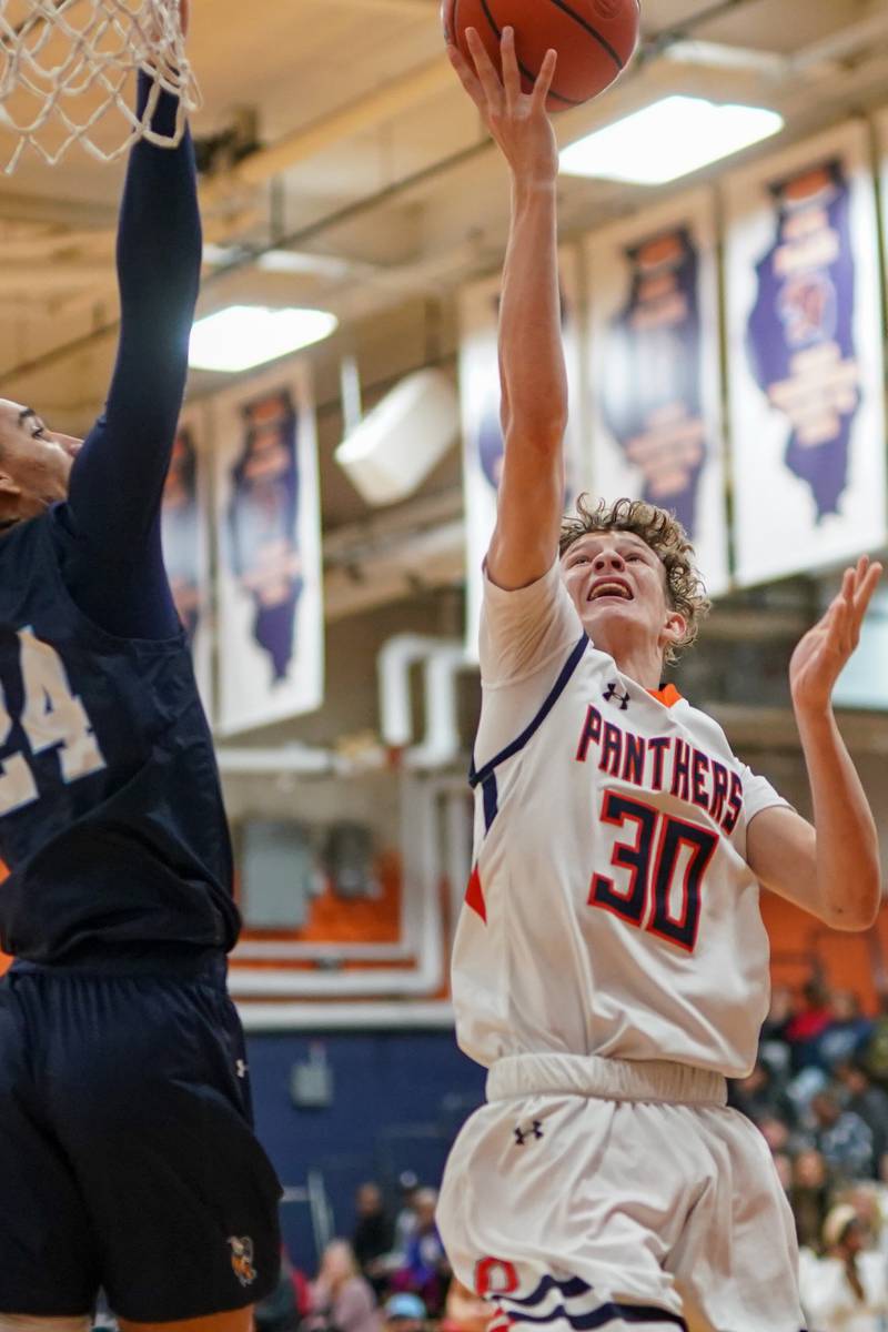 Oswego’s Brayden Borrowman (30) drives to the basket against Rockford Guilford’s Wonyae Sneed (24) during a hoops for healing basketball tournament at Oswego on Monday, Nov. 25, 2024.