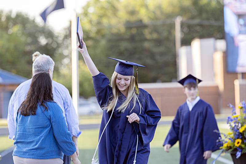 Sterling High School graduate Madison Schmitt hoists her diploma in the air following commencement Friday, May 26, 2023.