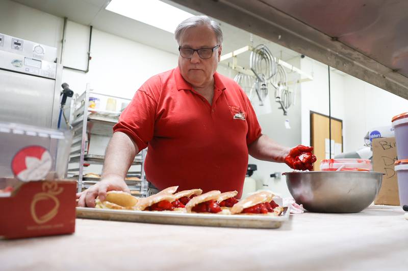 Bruce Aronson, owner of the Donut Den, prepares a tray of strawberry paczki doughnuts. Donut Den has nine different flavors of the popular Polish doughnut. Monday, Feb. 28, 2022, in Joliet.