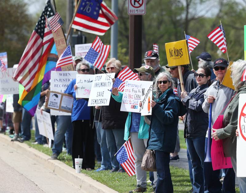 Protesters hold signs along Sycamore Road Saturday, May 3, 2025, at Hopkins Park in DeKalb during a May Day Rally for Democracy to protest against Trump administration policies.
