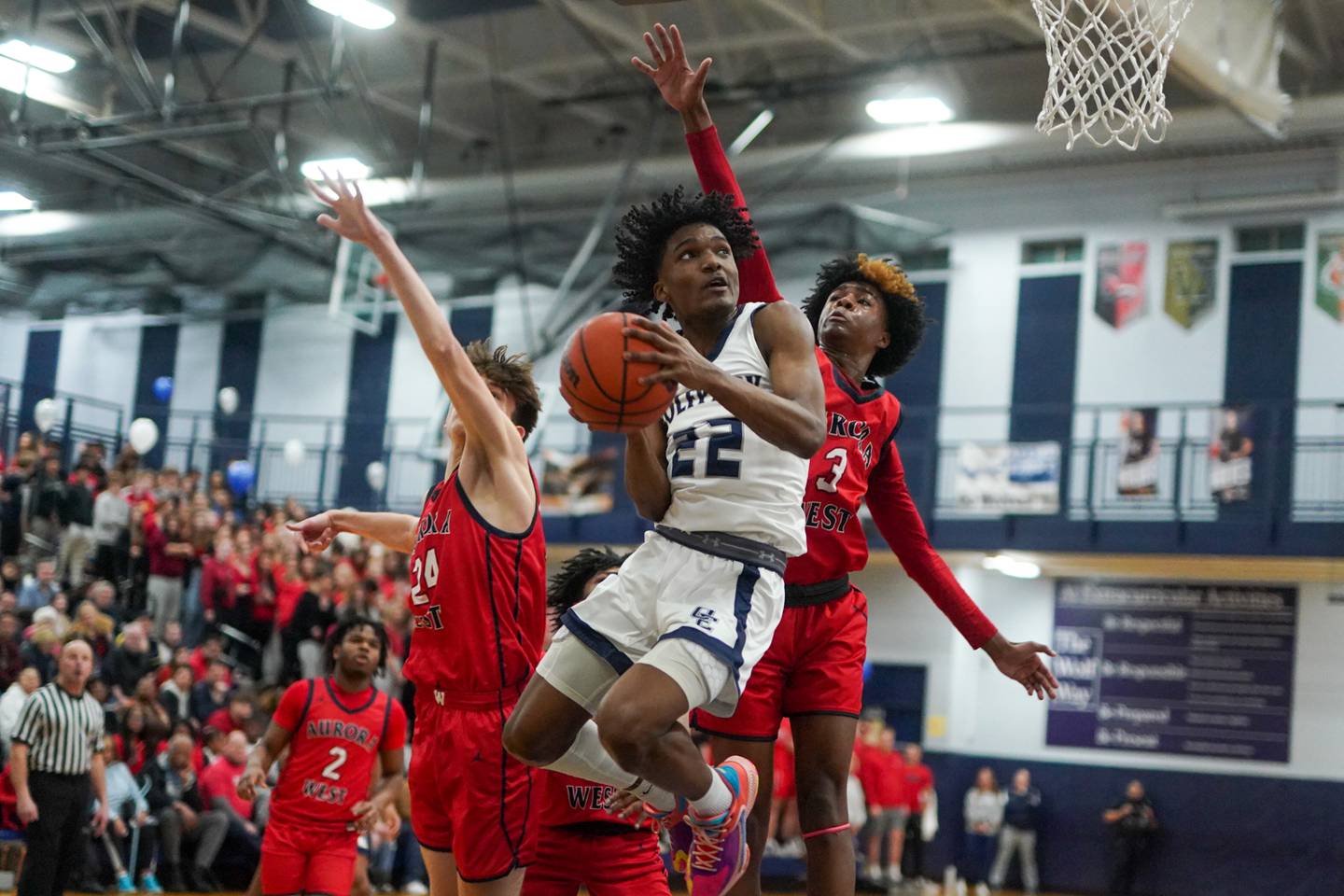 Oswego East's Jehvion Starwood (22) drives to the basket against West Aurora's Gabriel Gonzales (24) and Jayvyn Marion (3) during a basketball game at Oswego High School on Friday, Feb 2, 2024.