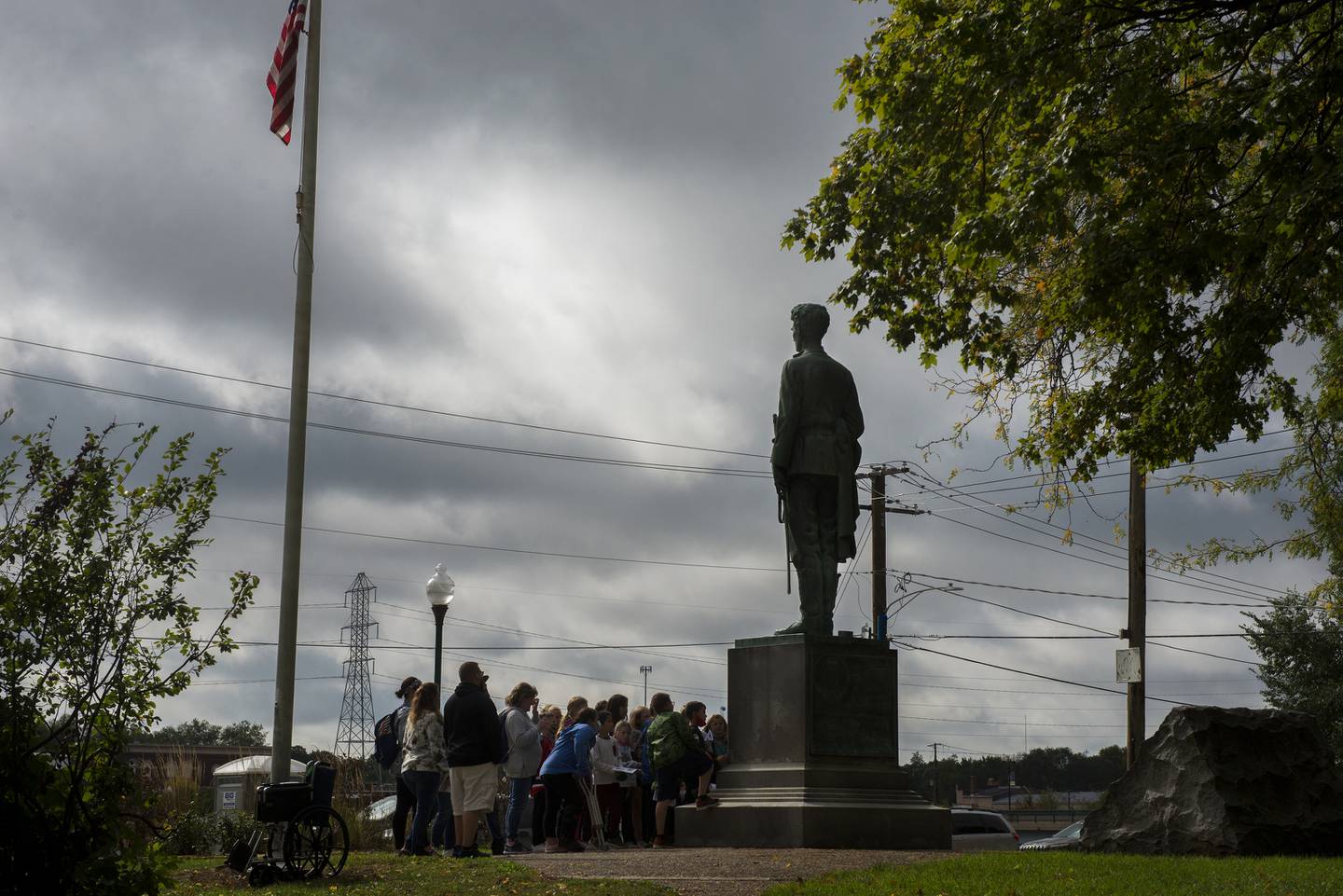 Fourth graders gather around the young statue of Lincoln to learn about his service in the Black Hawk War.