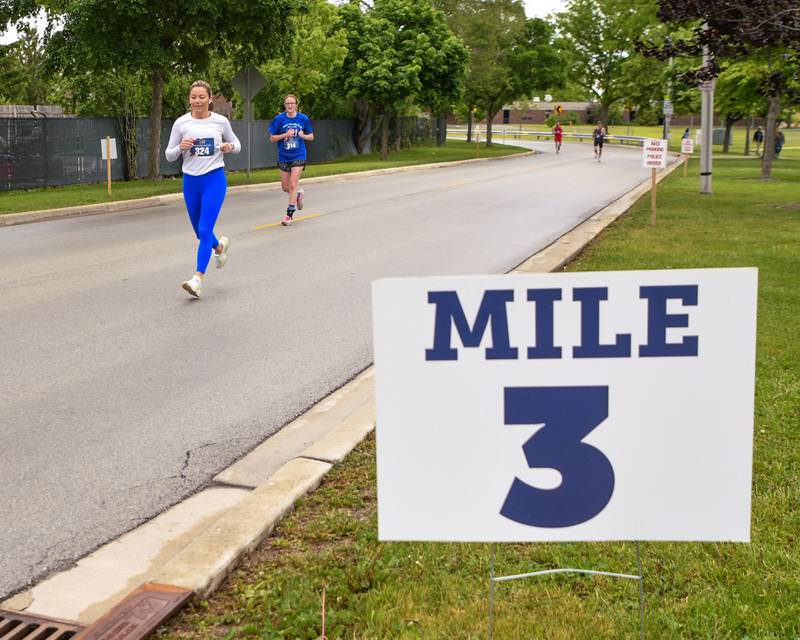 Dana Mckinniss, left and Danielle McCormick pass the 3 mile sign on the home Strach in completing the Race to the Flag 5k on Sunday May 25, 2025, held at Ty Warner Park in Westmont.
