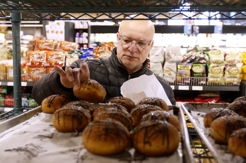 Nick Finia of McHenry licks his fingers after selecting a paczki Wednesday, Feb. 15, 2023, as he shops at Deli 4 You, 1501 S. Randall Road in Algonquin. Area bakeries are prepping for the lead-up to Lent when paczki are traditionally eaten. Deli 4 You will make and sell around 30,000 paczki this week.