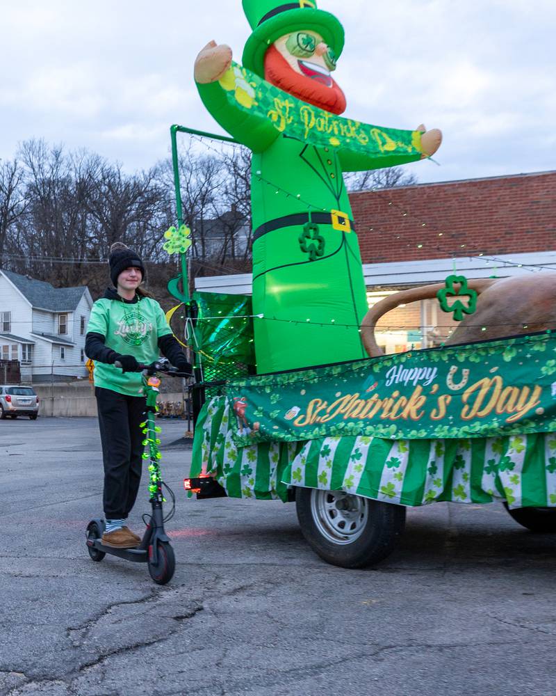 Marina Berkland rides scooter past float at the St. Patricks Day parade on Tuesday, March 14, 2026 on Main Street in Marseilles.