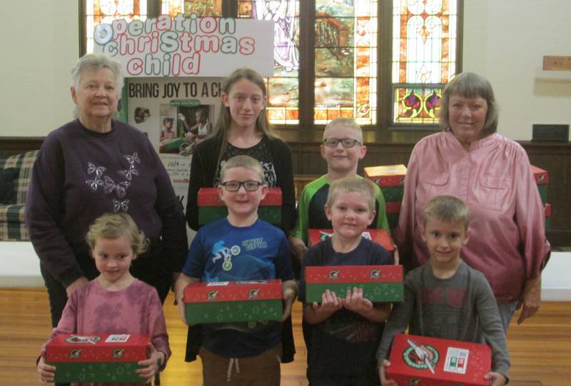 Pictured is Gerri Henze, back row left, chairperson of the Congregational Care Team,  along with several Sunday School children and Linda Oleson, back row right, member of the Congregational Care Team, and the boxes that will travel to children all over the world.