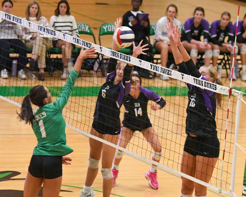 Downers Grove North's Sienna Shelton, center, and teammate Jennifer Buehler, right, try to block a spike by York's Amalia Toliopoulos (1) during the game on Tuesday Oct. 22, 2024, held at York High School in Elmhurst.